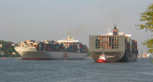 Das Bild zeigt zwei Containerschiffe auf der Elbe, die sich begegnen und einander vorbei passieren