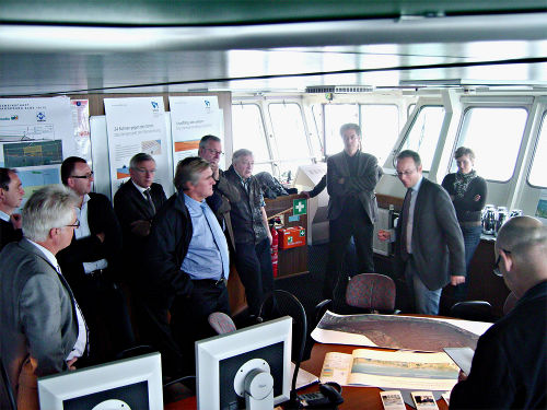 Das Bild zeigt eine Pressefahrt im Innenraum in einem Schiff. Es sind mehrere Menschen zu sehen.